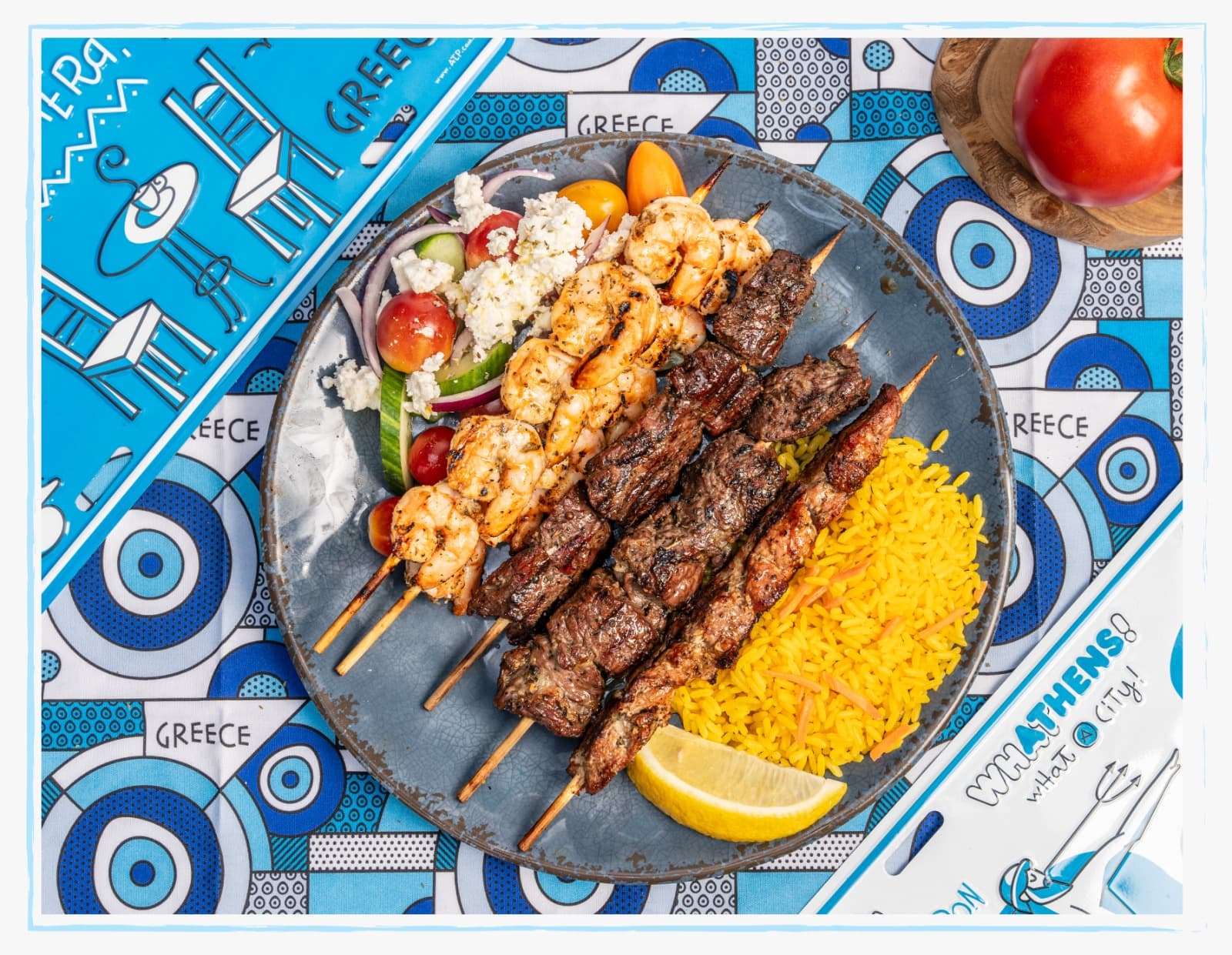 Greek souvlaki skewers with rice pilaf, Greek salad, and grilled shrimp on traditional plate