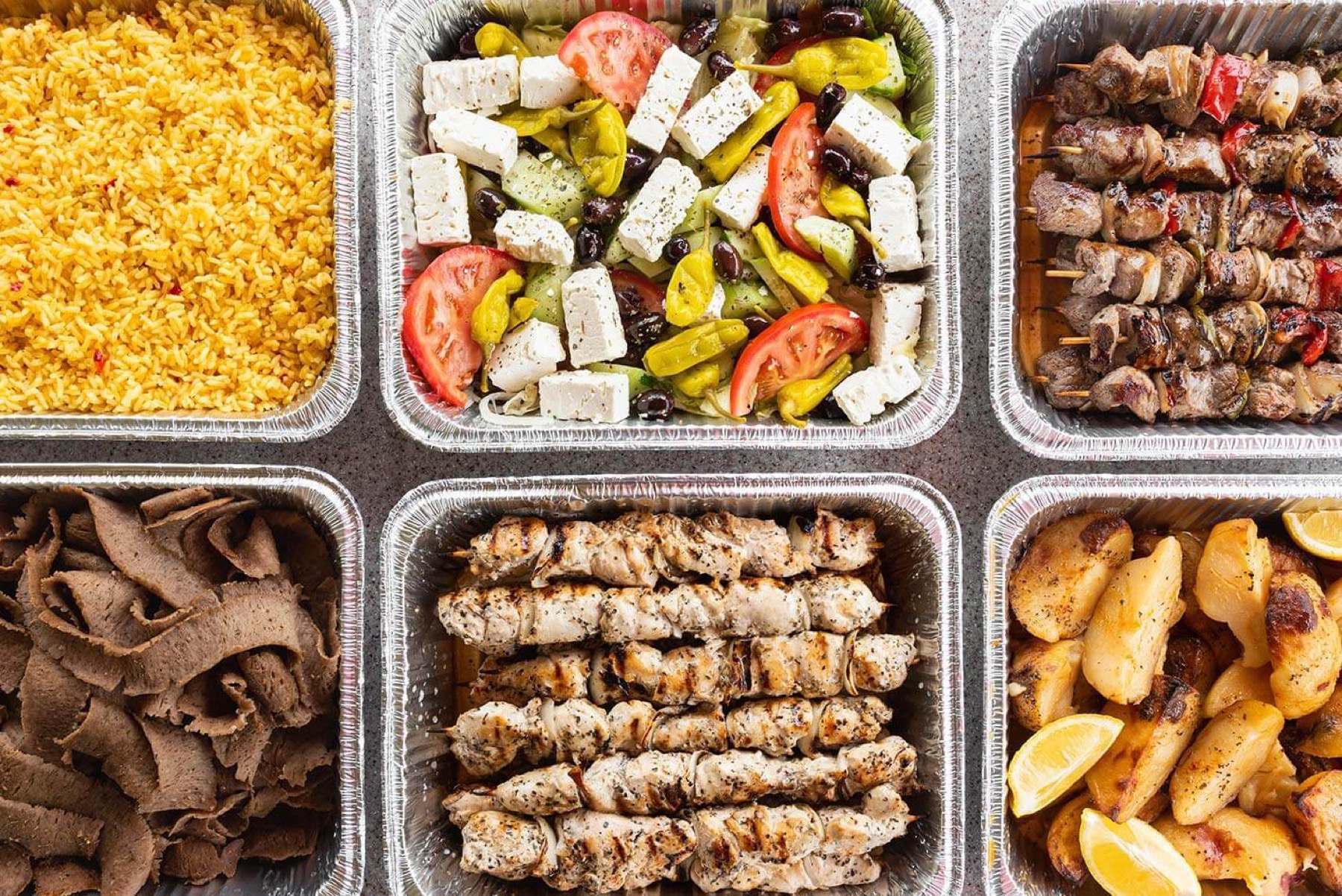 Gyro Bar catering trays with grilled proteins, toppings, salads, and sides